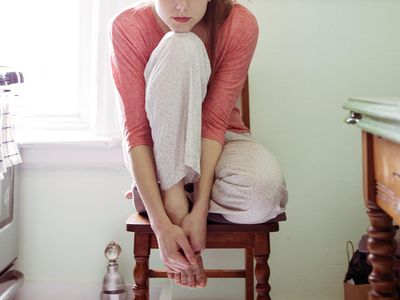 Young Woman Sitting In Kitchen Alone