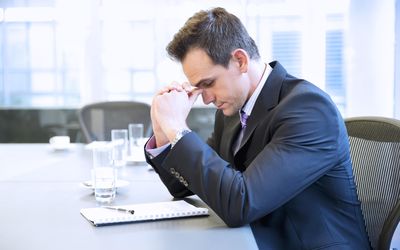 Businessman with head in hands in conference room.