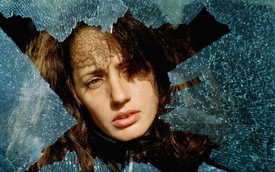 Woman peering through a broken glass window