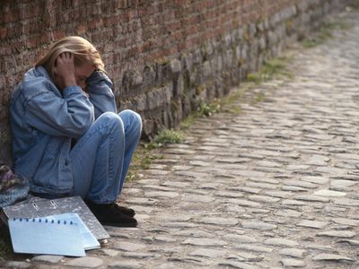 Troubled teenage girl seated by wall.