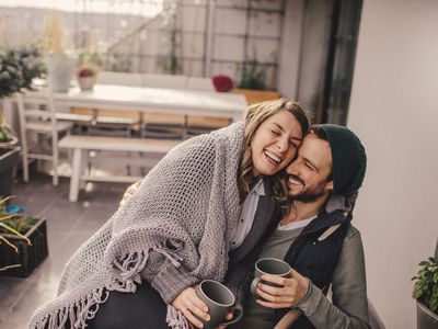 Photo of a young couple taking a few minutes off to relax and drink coffee on their balcony, on a beautiful autumn day