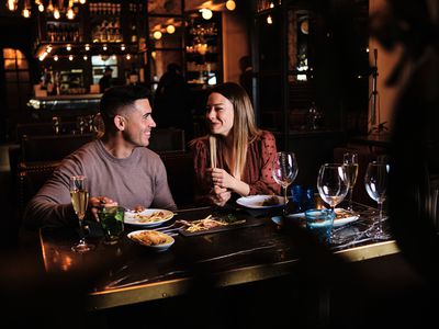 Portrait of young romantic couple on a date at the restaurant. Couple looking at each other and having fun together. 