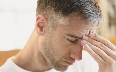 Close up of man with headache touching forehead