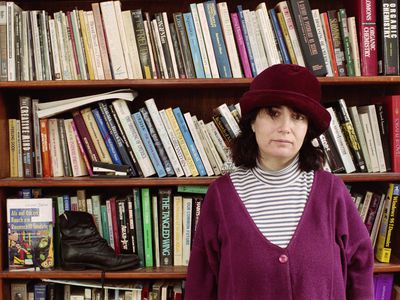 a woman standing in front of a bookshelf full of books