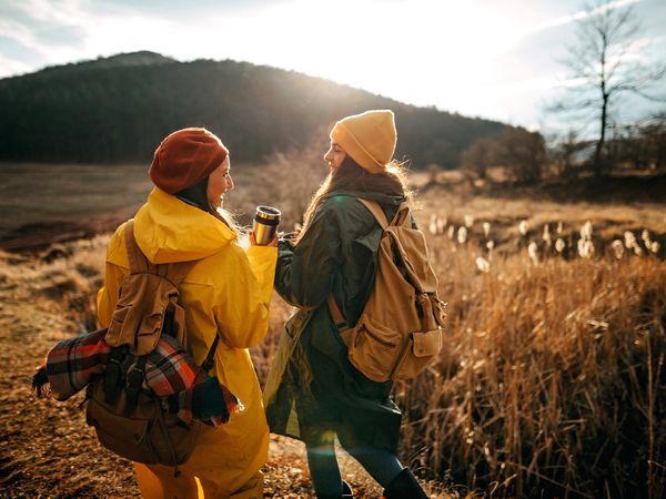 Two women relaxing in nature, they love autumn and each other, drinking hot drink