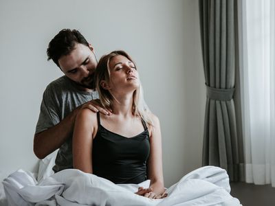 couple in bed, man is giving woman a shoulder massage