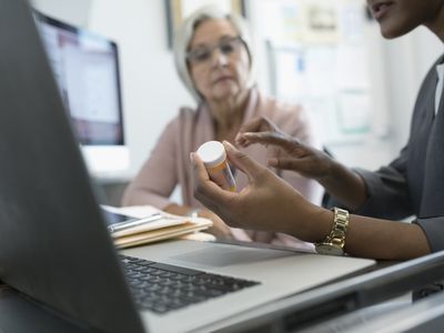 Female doctor prescribing mediation to senior patient in clinic office