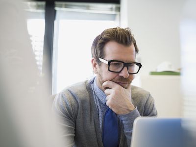 Focused businessman working at laptop hand on chin