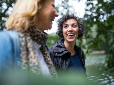 Happy mature woman looking at friend in forest