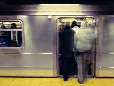 Passengers stepping in to crowded train, rear view (blurred motion)