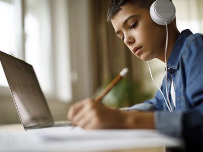 Teenage boy listening to music while doing homework