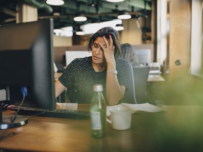 Upset woman with her hand on her head at her office desk