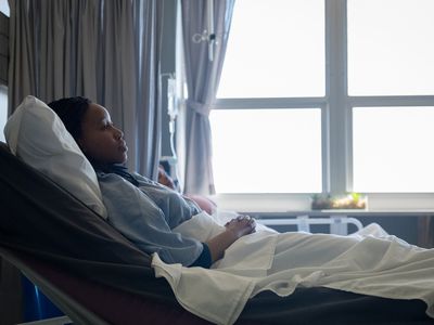 Black woman in hospital bed looking sad