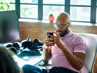 Mid adult man with beard and glasses texting in office