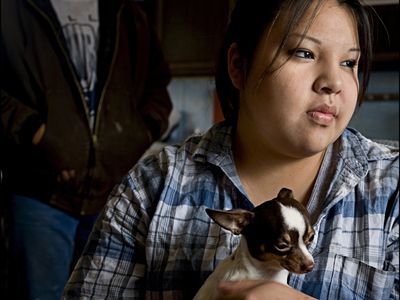 sad girl holding a chihuahua looking out of window