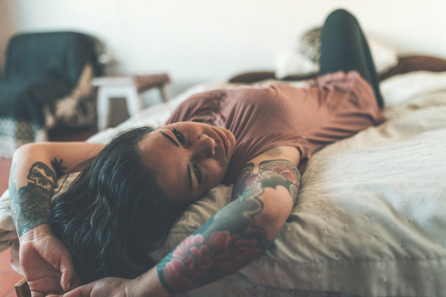 tattooed person laying on bed relaxing