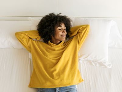 Smiling woman with closed eyes lying on bed