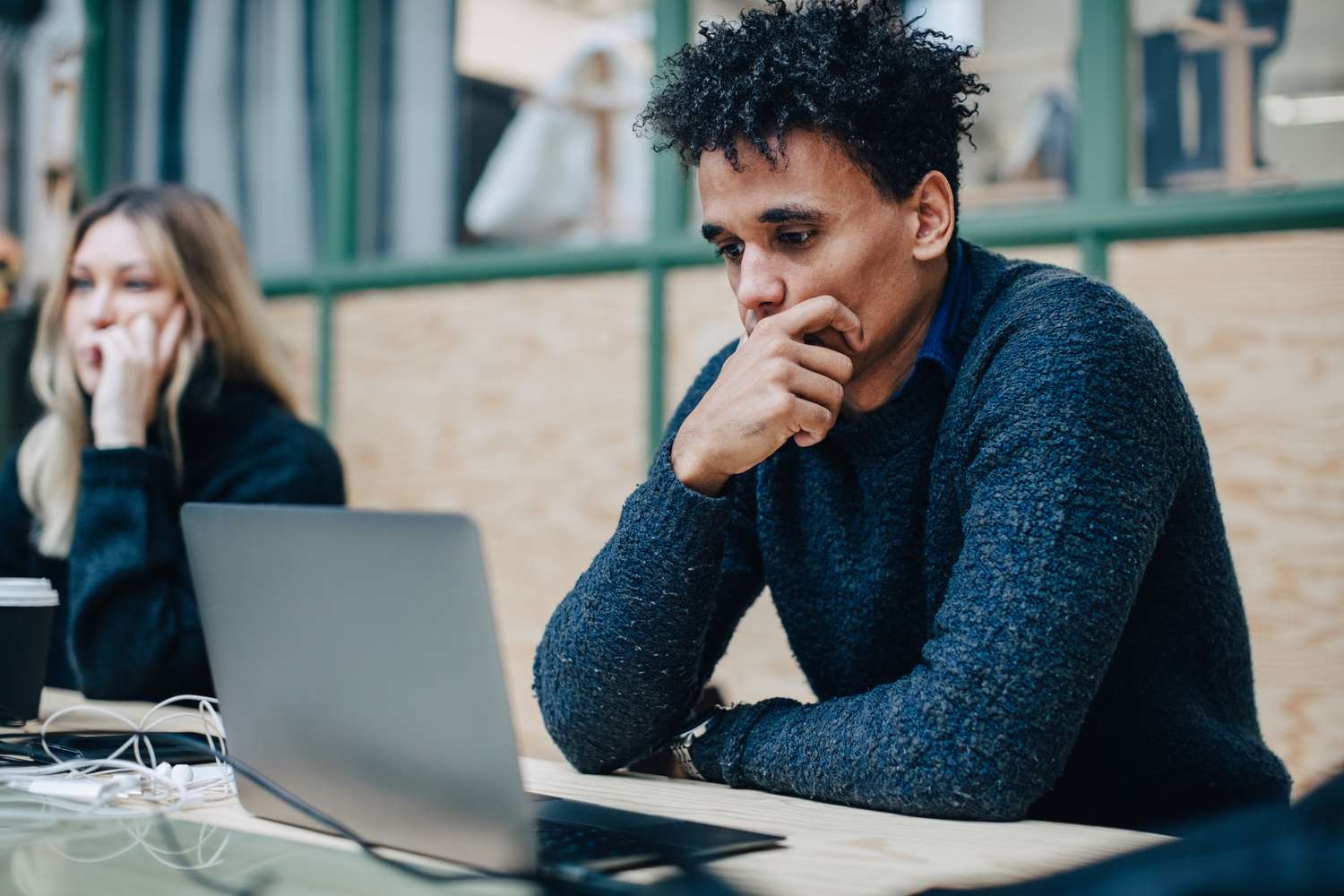 Serious worried colleagues with laptop on desk sitting in office