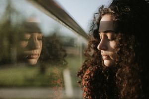 A woman with a sad expression looking out the window.