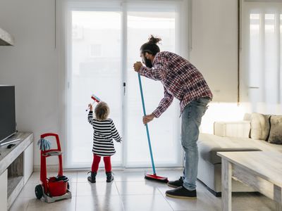 Father and little daughter cleaning the living room together