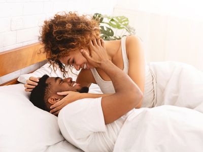 Happy black young couple kissing in bed