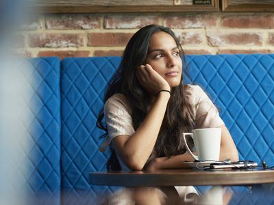 Woman sitting in contemplation at a cafe table