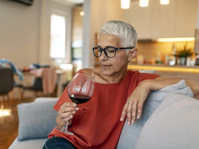 Mature woman sitting on the couch with a glass of wine