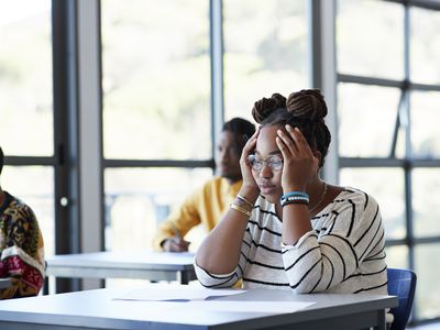 Worried student sitting with head in hands at desk 