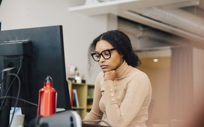 Focused computer programmer working on laptop at desk in office