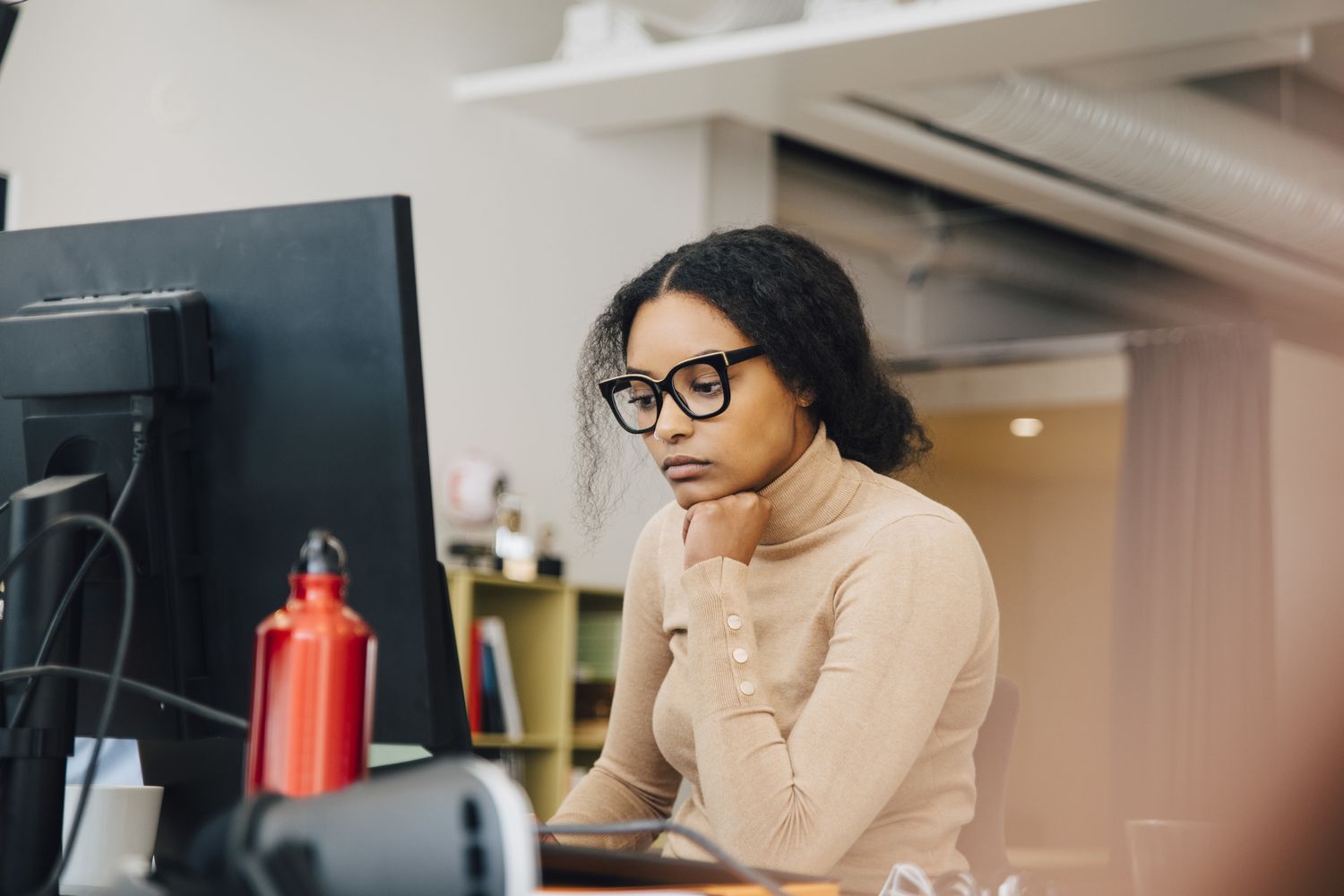 Focused computer programmer working on laptop at desk in office