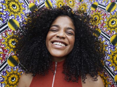 Close-up portrait of happy woman standing against patterned wall