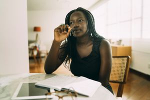 Student learning at home. African woman sitting at home and writing homework.