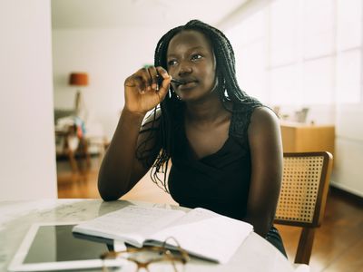 Student learning at home. African woman sitting at home and writing homework.