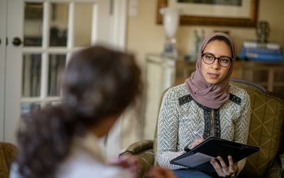 An image of a woman seated in an office speaking to a therapist.