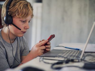 Boy listening to music and using his mobile phone and laptop