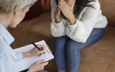 Psychologist Taking Notes Talking With Crying Woman In Office, Cropped 