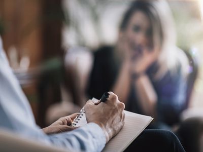 A therapist taking notes as a client talks about her problems.