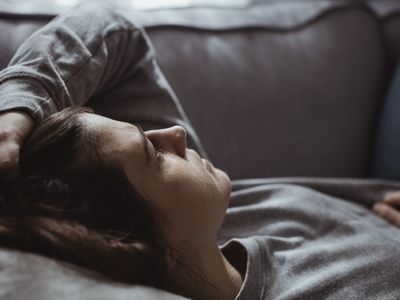 woman laying down on sofa looking anxious and sad