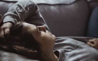 Close-up of sad woman lying on sofa at home