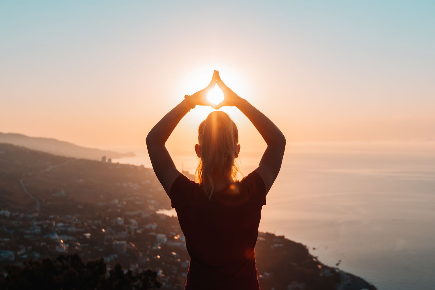 Woman at sunset with hands in air.