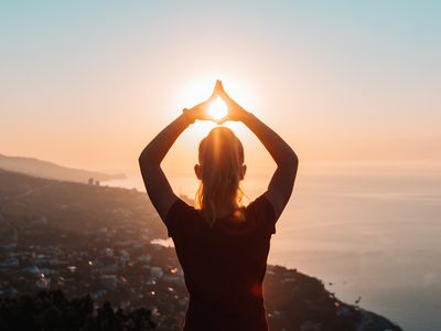 Woman at sunset with hands in air.