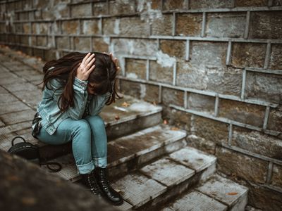 Woman on stairs with head in hands.