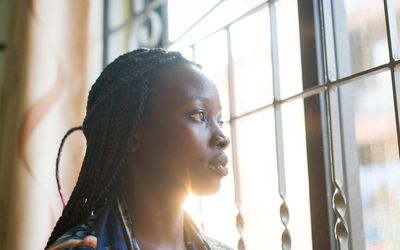 Women looking through window contemplating and thinking at home