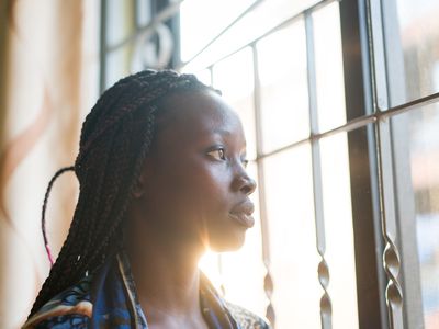 Women looking through window contemplating and thinking at home