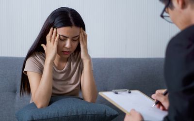 Sad woman with depression having consultation with psychiatrist in hospital mental health service center