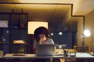 Shot of a young businesswoman looking stressed while using a laptop during a late night at work