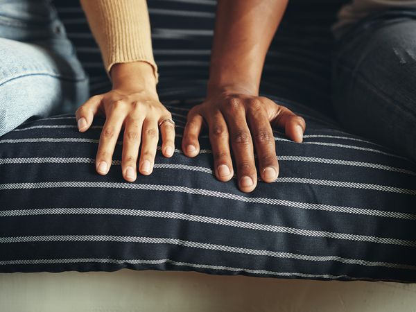 Closeup shot of an unrecognizable couple resting their hands alongside each other on a couch