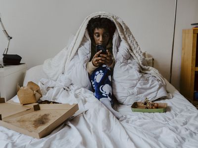 Young woman using smart phone while sitting in bedroom