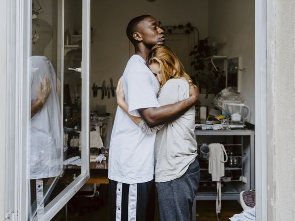 Son consoling depressed woman seen through window at home