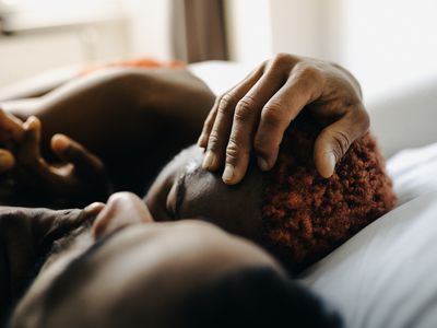 Two men embracing while laying in bed together after meeting up using a dating app